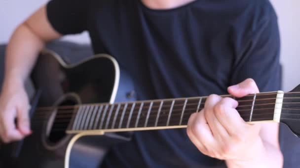 caucasian man playing chords in a black acoustic guitar. Selective focus on left hand - Záběry, video