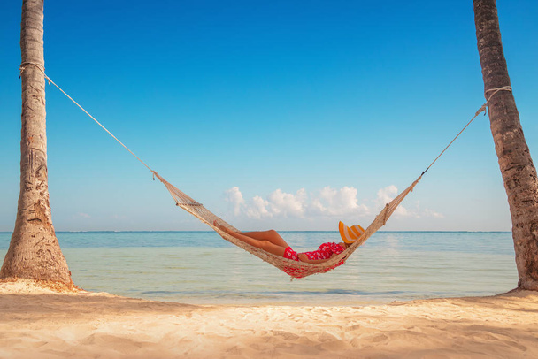 Młoda dziewczyna odpoczywająca w hamaku pod wysokimi palmami, tropikalna plaża - Zdjęcie, obraz
