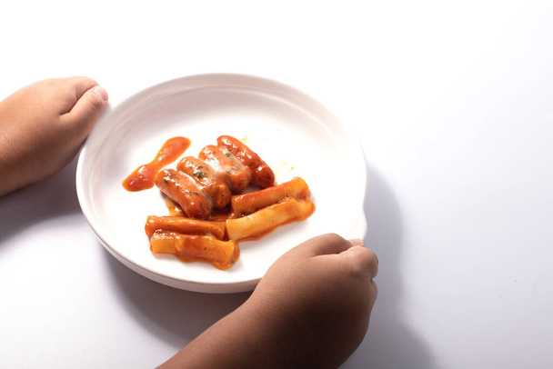 Egy kéz kezében egy Tteokbokki koreai étel egy fehér étel - Fotó, kép