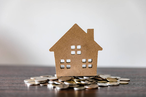 Домашняя модель на монетах на деревянном столе и белом фоне, деньги, финансы, бизнес, концепция недвижимости
 - Фото, изображение