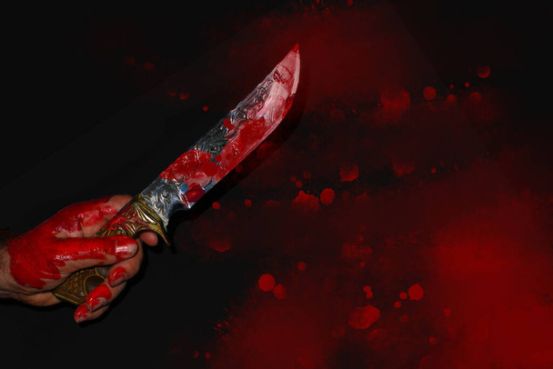 mężczyzna ręka z krwawiącym nożem na ciemnym tle - Zdjęcie, obraz