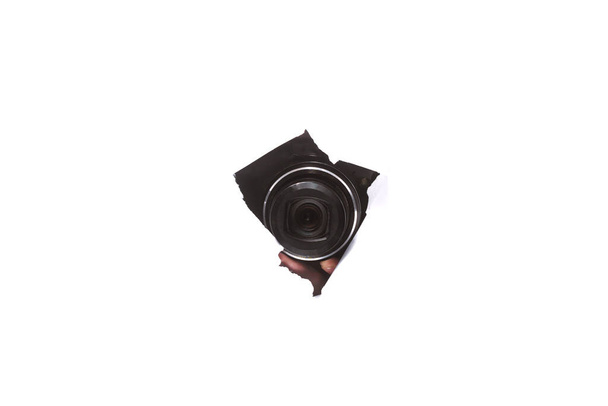 fotocamera door een gat in papier op geïsoleerde witte achtergrond. close up, kopieerruimte - Foto, afbeelding