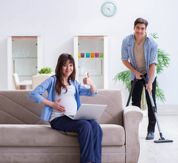 Man helpt zwangere vrouw bij het schoonmaken - Foto, afbeelding