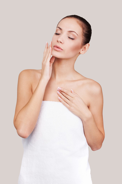 Woman wrapped in towel touching her face - Photo, Image