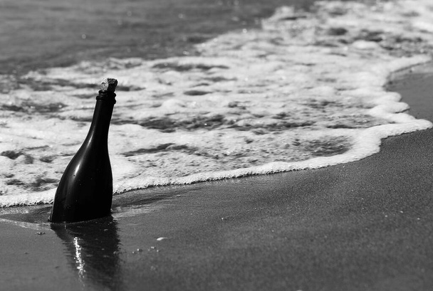 czarna butelka znaleziona na brzegu morza i może zawierać mapę skarbów - Zdjęcie, obraz