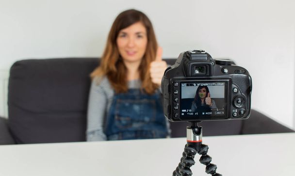 Vonzó fiatal lány videofelvételt készít a kamerájával egy fehér asztal tetején.. - Fotó, kép