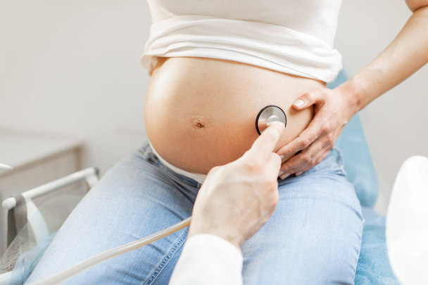 Доктор слушает беременную женщину в животе - Фото, изображение