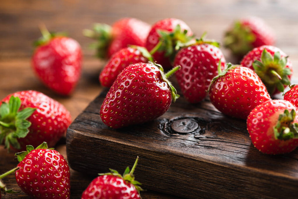 Fresh strawberries on a wooden background. Closeup view. Red summer berries harvest - 写真・画像