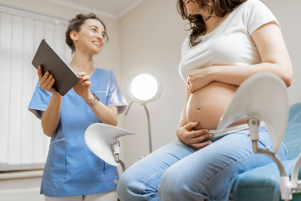 Νοσοκόμα με έγκυο γυναίκα κατά τη διάρκεια ιατρικής εξέτασης - Φωτογραφία, εικόνα