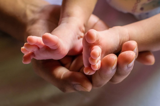 Nogi noworodka spoczywające na dłoni matki.Planowe skupienie się na opuszkach palców - Zdjęcie, obraz