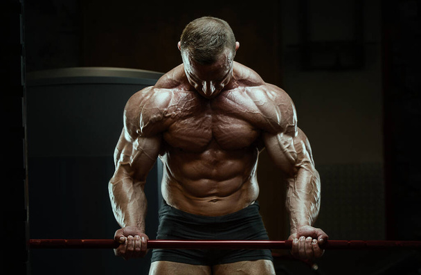 Bodybuilder pumping up biceps muscles workout fitness and bodybuilding healthy concept background - muscular fitness men doing arms exercises in gym naked torso. Handsome strong athletic rough man - Valokuva, kuva