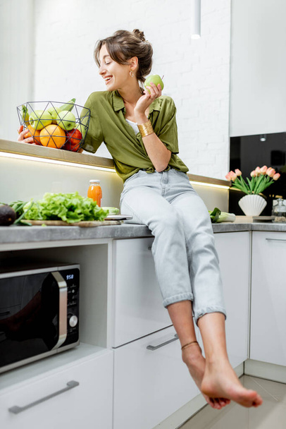 Portrait of a young woman with healthy food on the kitchen - Foto, Imagem