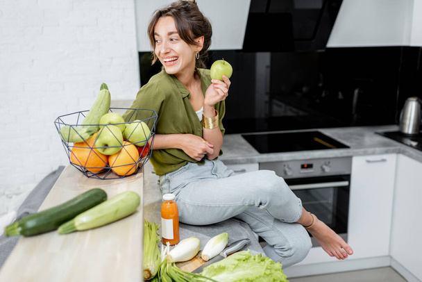 Portret van een jonge vrouw met gezond eten in de keuken - Foto, afbeelding
