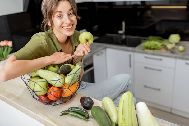 Egy fiatal nő portréja egészséges ételekkel a konyhában. - Fotó, kép