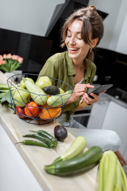 Donna con cibo sano e telefono in cucina - Foto, immagini