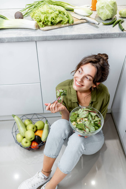 Жінка їсть здоровий салат на кухні вдома
 - Фото, зображення