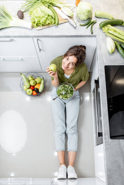 Женщина ест здоровый салат на кухне дома - Фото, изображение