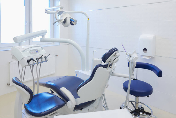 Beyaz ve mavi mobilyaları, diş sandalyeleri, yüksek hızlı matkapları olan yeni bir dişçi bürosu. Dişçinin ofisi.. - Fotoğraf, Görsel