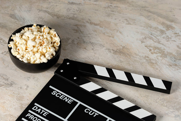 Clapper board with popcorn. Movie concept. Clapperboard on a textural background. Close-up. - Zdjęcie, obraz