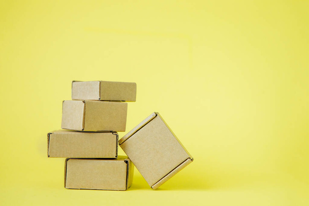 Cardboard boxes of various sizes on yellow background - 写真・画像