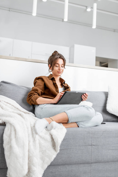 Woman with a tablet on the couch at home - Fotoğraf, Görsel