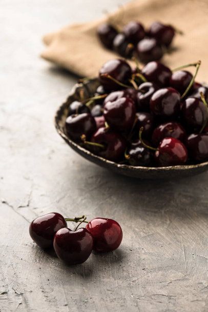 Ripe sweet cherry in ceramic bowl at concrete background - Photo, image