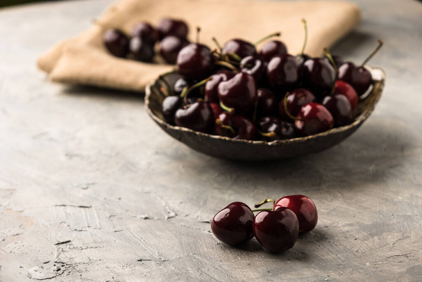Ripe sweet cherry in ceramic bowl at concrete background - Photo, image
