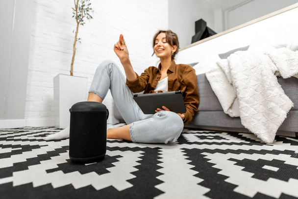 Woman with a smart speaker and tablet at home - Foto, Bild