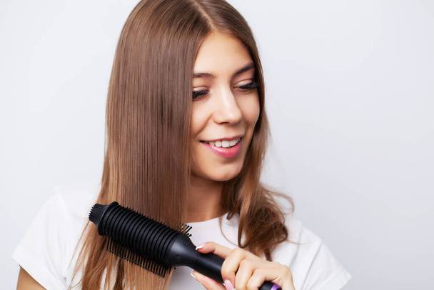 Krásná mladá žena používá rovnátka na vlasy, aby krásný styl - Fotografie, Obrázek