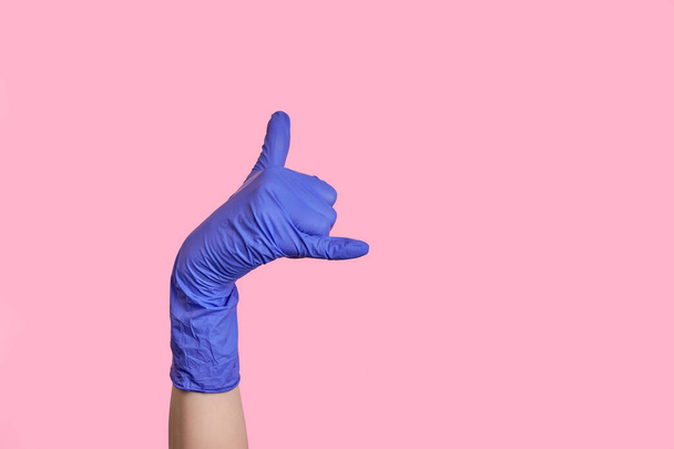 Eine Hand in einem medizinischen Latex-Handschuh macht eine Geste, rufen Sie mich an. isoliert - Foto, Bild