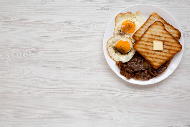 Domowej roboty zdrowe jajka Sunnyside Śniadanie na białym talerzu na białej drewnianej powierzchni, widok z góry. Leżał płasko, nad głową, z góry. Przestrzeń kopiowania. - Zdjęcie, obraz