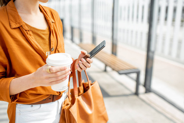 Nainen kahvikupin ja puhelimen kanssa ulkona - Valokuva, kuva