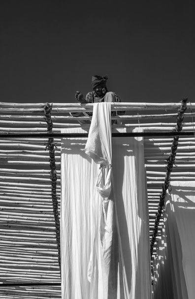 Indian man hanging cotton clothes to dry under the sun - Foto, Bild