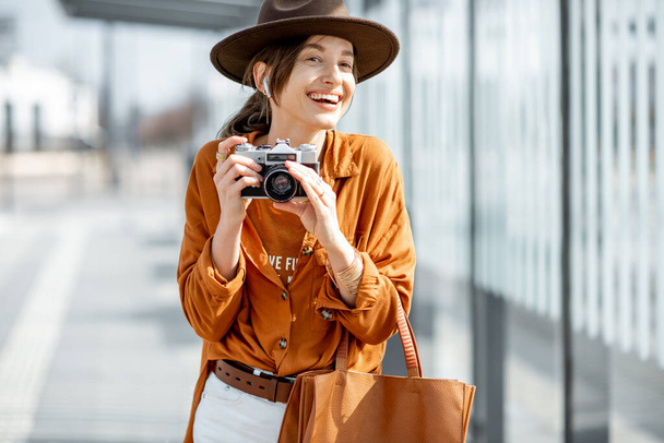 Jeune femme voyageant avec un appareil photo dans la ville moderne - Photo, image