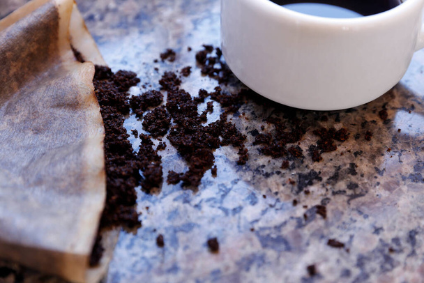 table with coffee grounds in the strainer and white cup with coffee - Foto, immagini
