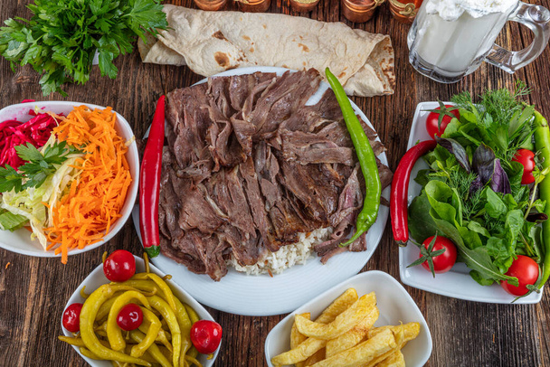 Traditioneller türkischer Dönerspieß, Shawarma oder Gyros mit Flava und Reis. Türkisches, griechisches oder mittelöstliches Döneressen auf Holztischhintergrund. - Foto, Bild