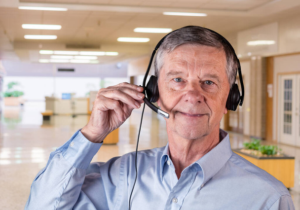 Hombre mayor usando auriculares para comunicarse con el equipo o los clientes
 - Foto, Imagen