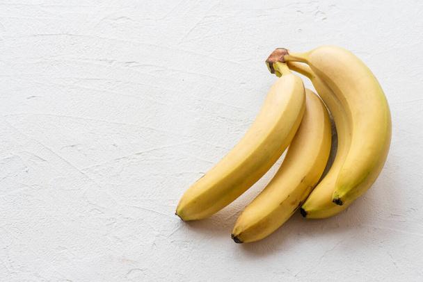 Pile of ripe bananas on a white table background with copy space. - Fotó, kép