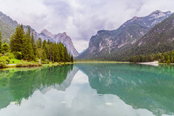 Wide lake between mountains covered with forest - Photo, Image