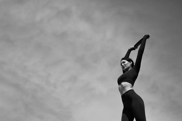Black and white photo of the girl doing exercises to warm up the muscles by using elastic bands for exercise. - Foto, afbeelding