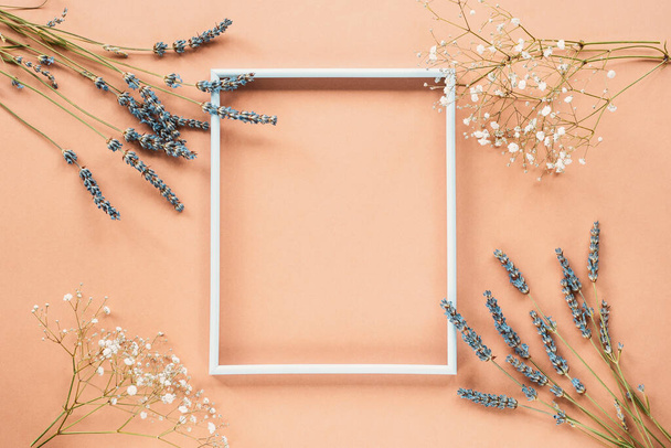 White frame with lavender blossom and gypsophila flowers on pastel pink background, flat lay, copy space - Photo, Image