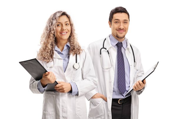 Young female and male doctors holding clipboards isolated on white background - Фото, зображення