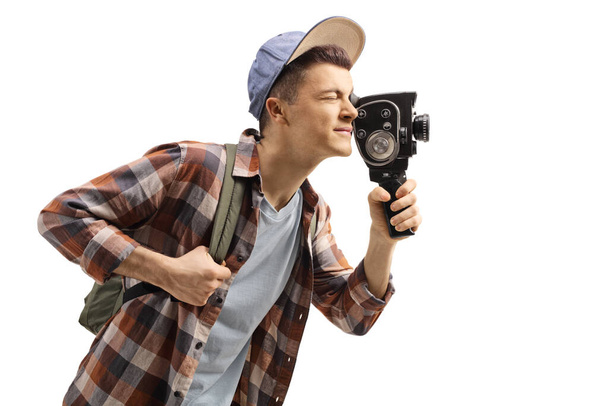 Male student with a backpack recording with a vintage 8mm camera isolated on white background - Photo, image