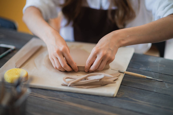 Womans vingers toevoegen en aanpassen van een klei deel op een toekomstig keramisch product. - Foto, afbeelding