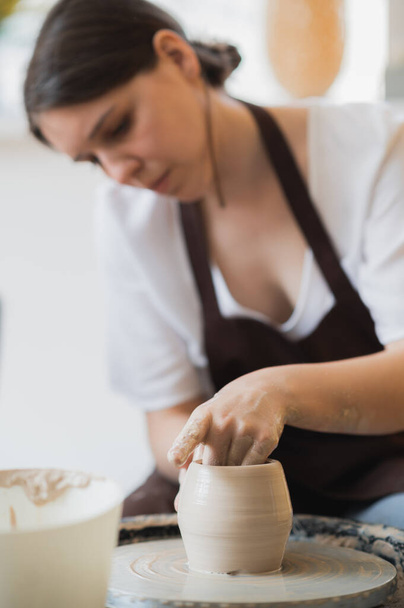 Close-up of potter making pot in pottery workshop. Using sponge and water for moisturizing clay. - Photo, Image
