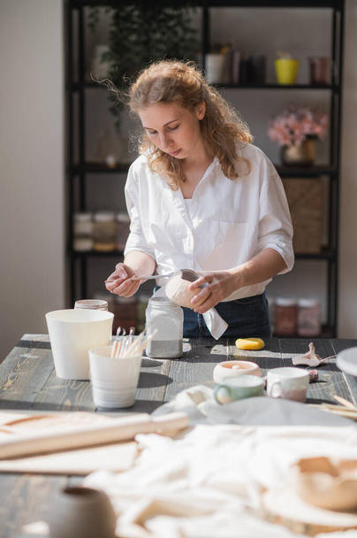 Primo piano di una donna che fa stoviglie in ceramica e ceramica in officina, lavorando con argilla e smalto. - Foto, immagini