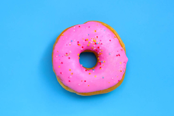 Rosafarbener Donut auf blauem Hintergrund. Ansicht von oben - Foto, Bild