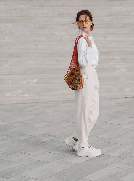 Beautiful woman holds eco craft bag with vegetables. - 写真・画像