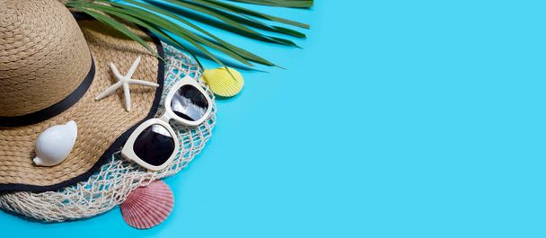 Sombrero de verano con gafas de sol sobre fondo azul. Disfruta del concepto de vacaciones. Copiar espacio - Foto, imagen