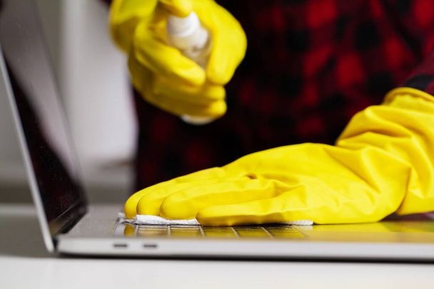 Κοντινό πλάνο του καθαριστή σε κίτρινα γάντια σκουπίζει σκόνη στο γραφείο - Φωτογραφία, εικόνα